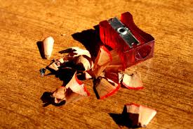 red plastic pencil sharpener with shavings on a wooden table